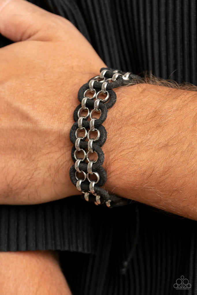 Distressed black leather cords snake around and through two silver chains around the wrist, resulting in a rustic edge. Features an adjustable sliding knot closure.  Sold as one individual bracelet.