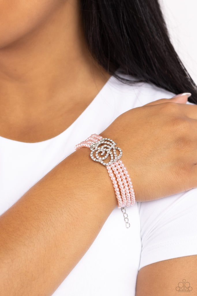 <p>Held together by dainty silver plates, four strands of baby pink pearls are threaded around the wrist. Encrusted in glassy white rhinestones, a glitzy silver rose blooms at the center of the wrist for a fierce floral statement.</p> <p><i>Sold as one individual bracelet. </i></p>